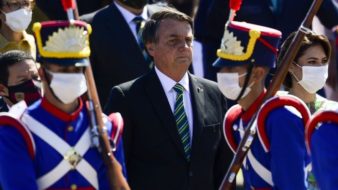 Bolsonaro está cercado de soldados vestidos de azul e acompanhado de sua esposa para o desfile do dia da independência.