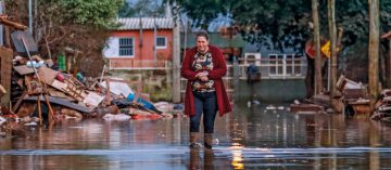 Mulher caminha em meio à enchente em Porto Alegre, em junho (Bruno Peres/Agência Brasil)